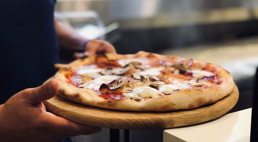 Person holding a pizza